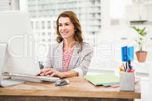 Smiling casual businesswoman working with computer