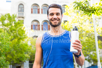 Handsome athlete smiling and holding bottle