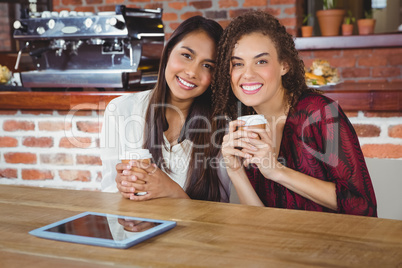 Pretty female friends enjoying a coffee using tablet pc