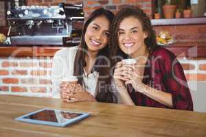 Pretty female friends enjoying a coffee using tablet pc