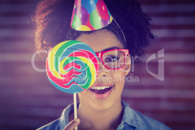 Portrait of a hipster hiding herself behind a lollipop