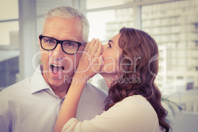 Casual businesswoman whispering secret to her colleague