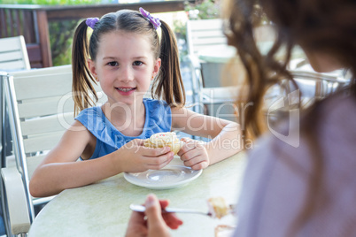 Mother and daughter enjoying cakes at cafe terrace