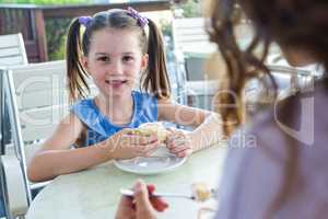 Mother and daughter enjoying cakes at cafe terrace