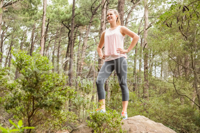 Smiling blonde hiker standing on rock