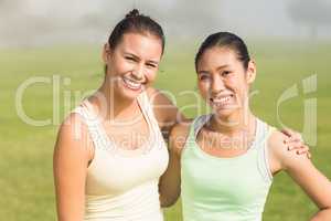 Smiling sporty women with arms around each other