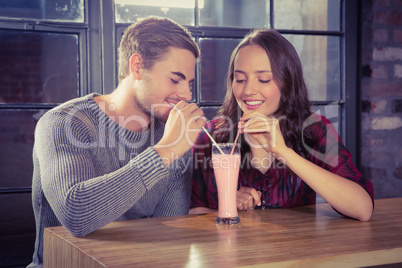 Smiling friends sharing smoothie