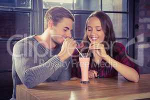 Smiling friends sharing smoothie