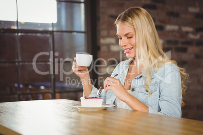 Smiling blonde enjoying cake and coffee