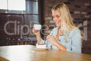 Smiling blonde enjoying cake and coffee