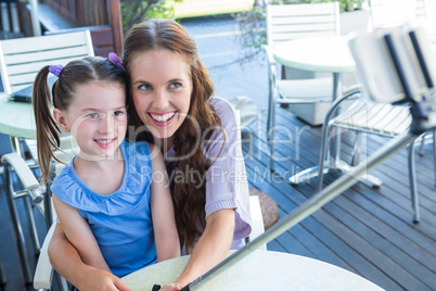 Mother and daughter using selfie stick at cafe terrace
