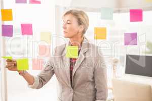 Casual businesswoman reading sticky notes