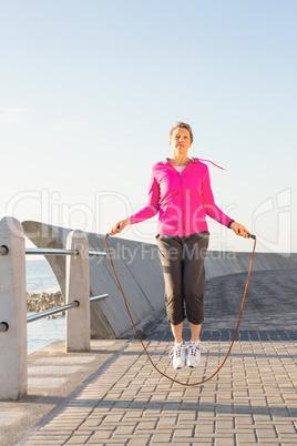 Sporty woman skipping at promenade