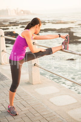 Fit woman stretching leg on railing