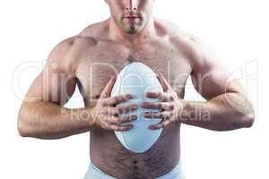 Shirtless rugby player holding ball