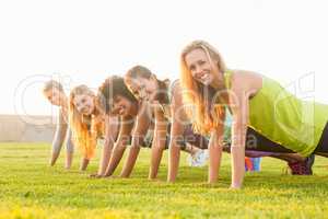 Smiling sporty women doing push ups during fitness class