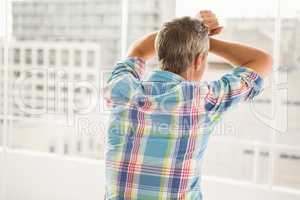 Rear view of troubled casual businessman leaning against window