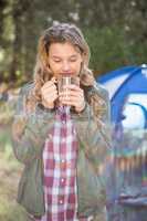 Pretty blonde camper enjoying beverage in front of tent