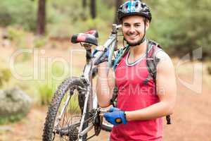 Happy handsome biker holding bike and looking at camera