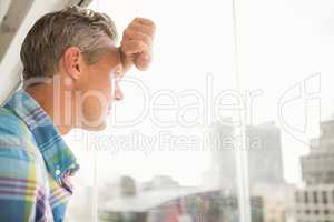 Troubled casual businessman leaning against window