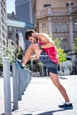 Handsome athlete doing leg stretching on a stake