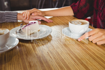 Couple holding hands and having coffee and cake together