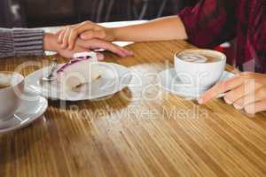 Couple holding hands and having coffee and cake together