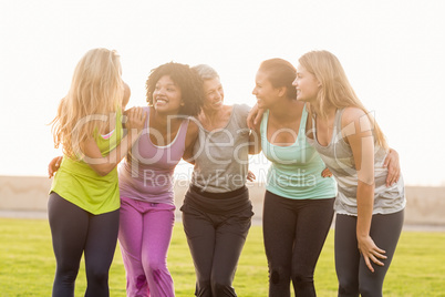 Smiling sporty women with arms around each other