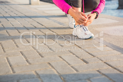 Sporty woman tying her shoelace at promenade