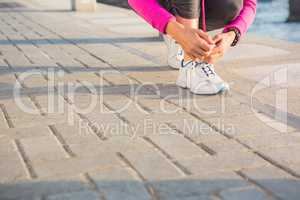 Sporty woman tying her shoelace at promenade