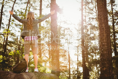 Carefree blonde hiker standing on stone with arms outstretched
