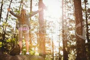 Carefree blonde hiker standing on stone with arms outstretched