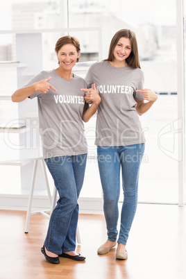 Smiling female volunteers showing their shirts