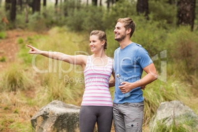 Young happy woman pointing in the distance next to her friend