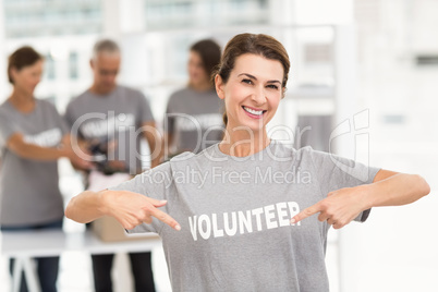 Smiling female volunteer pointing on shirt