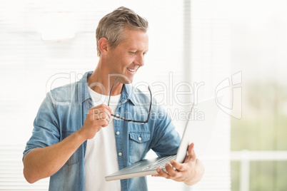 Smiling businessman holding a laptop