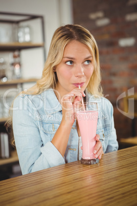 Pretty blonde drinking smoothie through straw