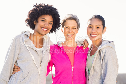 Smiling sporty women with arms around each other