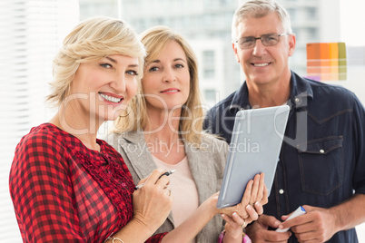 Smiling business team holding a tablet