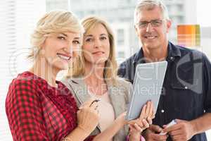 Smiling business team holding a tablet