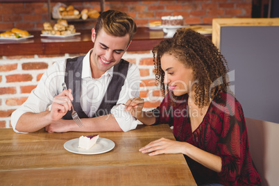 Young happy couple feeding each other with cake