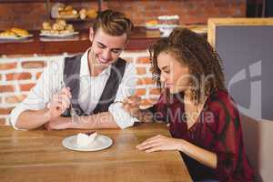 Young happy couple feeding each other with cake