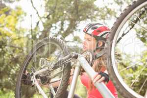 Smiling blonde athlete checking her mountain bike