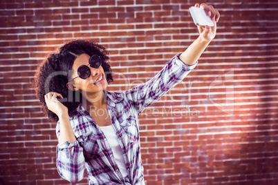 Attractive hipster taking selfies with smartphone