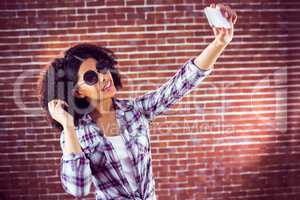 Attractive hipster taking selfies with smartphone