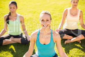 Smiling sporty blonde doing yoga with her friends