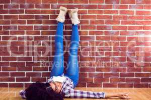 Attractive hipster lying on ground and holding legs up