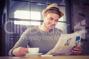 Handsome hipster having coffee and reading newspaper