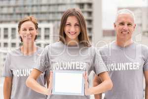 Smiling volunteers showing blank tablet