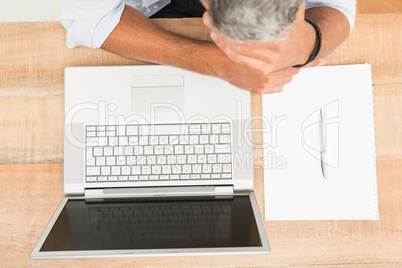 Exhausted casual businessman leaning on wooden desk